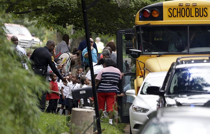 A police officer gives a high-five to students from Ronald E. McNair Discovery Learning Academy as they board school buses to take them to reunite with their parents as they were evacuated after reports of a gunman entered the school, Tuesday, in Decatur, Ga. All students and teachers are safe and a suspect is in custody after gunfire was heard at the Atlanta-area elementary school today. 