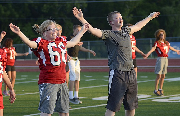 Millie Nelson (left) and her son, Charles, do jumping jacks during an exercise portion of Mom's Night for the Jefferson City Jays on Tuesday at Adkins Stadium. Mothers of the players wore their son's jerseys and participated in the drills and exercises the young men have been doing to prepare for the upcoming season.
