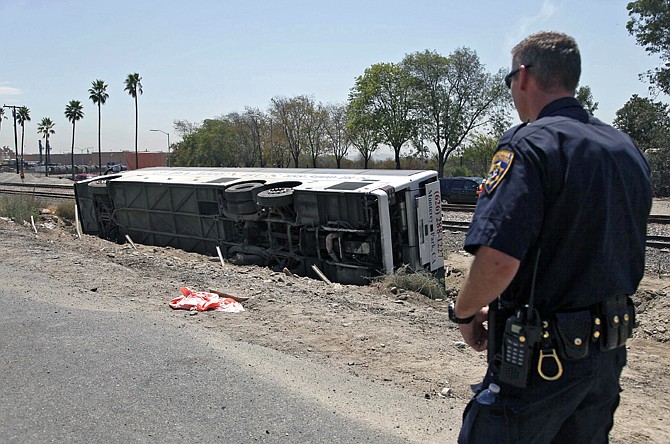 A highway patrol officer looks at a bus that crashed along the side of Interstate 210 in Irwindale, Calif., on Thursday. The bus carrying gamblers to a casino overturned on the Southern California freeway injuring more than 50 people on board. 