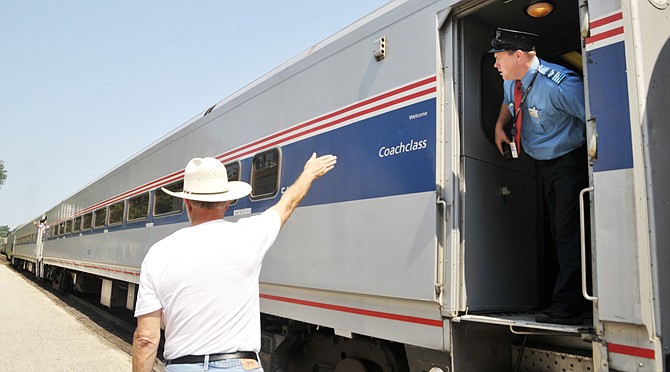 Charlie McCoy waves to the assistant conductor to indicate everyone is on board and ready to go as the train prepares to pull out of the Jefferson City station Friday morning. On board the train is conductor Jason Tuck, who checks forward and backward to make sure the loading area is clear. McCoy is one of the members of the Capital City Amtrak Friends group who volunteers at the Amtrak station on a regular basis.