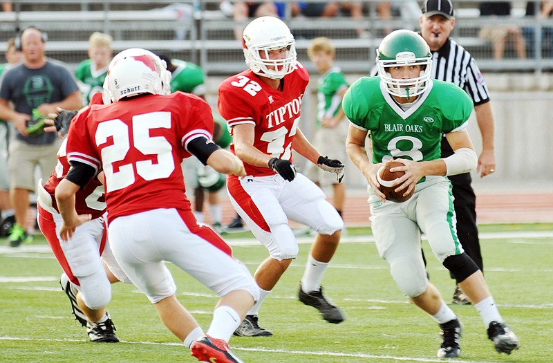 Blair Oaks backup quarterback Adam Schell looks to pitch the ball to a teammate while Tipton defenders Dylan Becker (25) and Daniel Burkett (32) close in during Friday's Jamboree at the Falcon Athletic Complex.