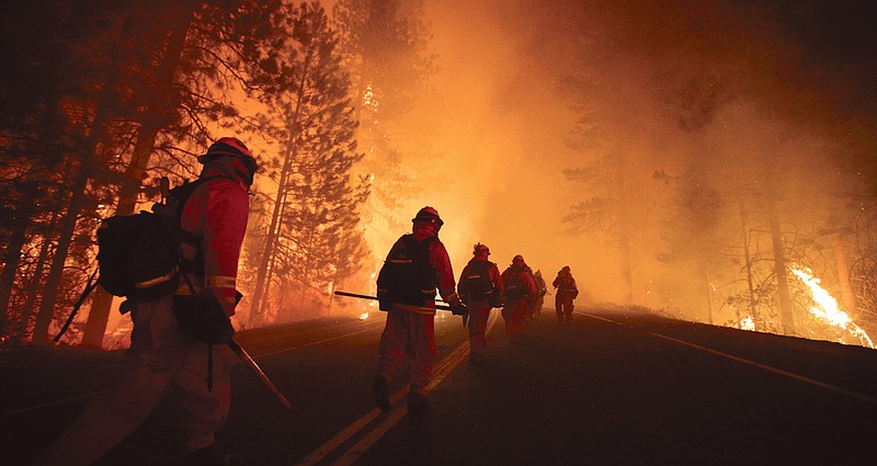 Firefighters walk along state Highway 120 as firefighters continue to battle the Rim Fire near Yosemite National Park, Calif.