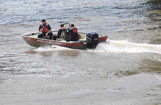 Jefferson City firefighters use their rescue boat as they help police investigate and recover a dead body that was found floating in the Missouri River Saturday morning.