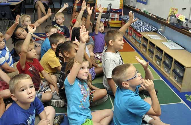 Students in Sara Borgmeyer's West School first grade class raise their hands to answer questions during math class. 