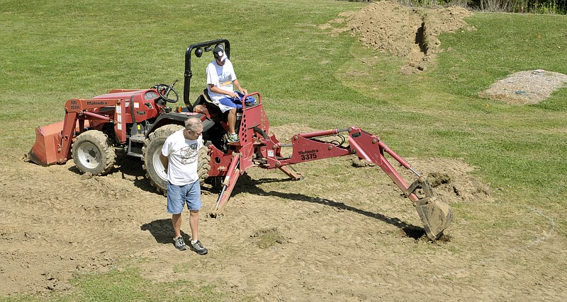 Kenneth Hackman, standing, and his son, Randy, have been hard at work in the yard of their Elston home as they prepare a layout for a garden railroad. Here, Randy digs an area outlined in white that will eventually be a small lake for the railroad. It will be named Rusk Lake after the neighbor who loaned them the tractor for the work. Some will create scale buildings for the project and can name those stores, stations and depots as they choose. They hope to have the rail in place and trains on the track to premier July 5, 2014.