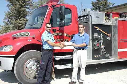 Andrew Korte, Safety Officer for California Rural Fire Protection District, accepts a check for a $1,000 grant from Jamie Rauba, FM Global Engineering Specialist. The funds are to be used for training supplies. 