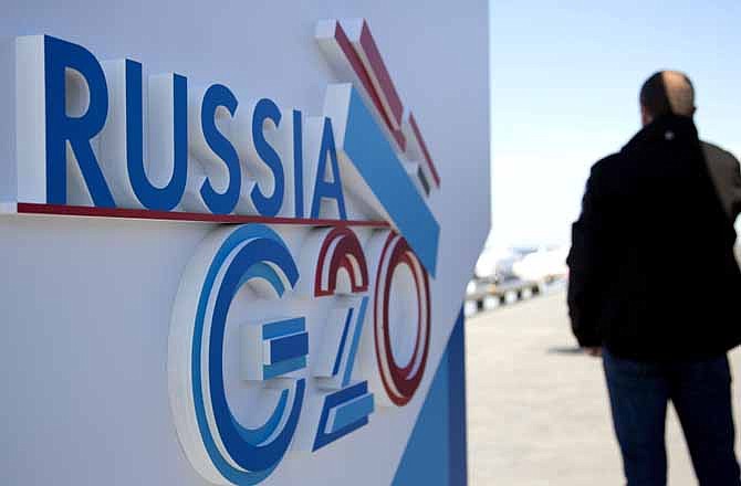 A journalist speaks on a cell phone next to a sign for the G20 summit in St. Petersburg, Russia on Wednesday, Sept. 4, 2013. The biggest economies, the United States, Europe, Japan, as well as China, are all expanding. And the leaders who will gather this week are more confident about their financial systems than at any time since they began meeting five years ago. 