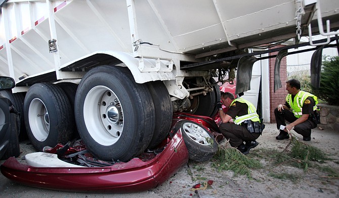 
Utah Highway Patrol troopers Mark Johnson, left, and Doug Whitlock inspect a trailer that crushed a vehicle before hitting a home Thursday in Bountiful, Utah. Bountiful police Sgt. Andrew Bryson says the truck's brakes went out and it rolled about half a block until it came to rest partly inside a house. No one was injured in the accident.