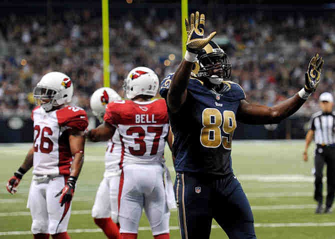 St. Louis Rams tight end Jared Cook celebrates after catching a 16-yard pass for a touchdown during the second quarter of an NFL football game as Arizona Cardinals safeties Rashad Johnson (26) and Yeremiah Bell (37) stand on the field on Sunday, Sept. 8, 2013, in St. Louis.