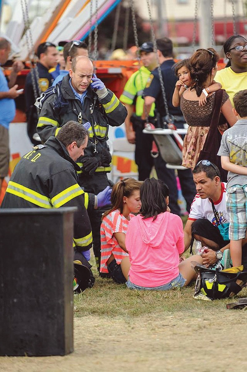 Two girls are tended to after 12 children were injured Sunday when a festival attraction that swings riders into the air lost power at a community fair in Norwalk, Conn,
