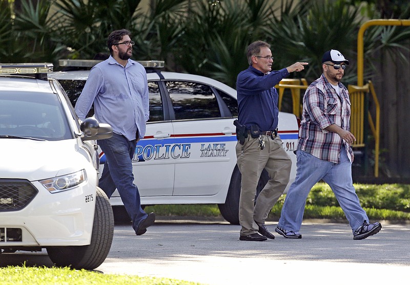 George Zimmerman, far right, is escorted to a home by a Lake Mary police officer, center, and Shawn Vincent, as assistant to his attorney, Monday, Sept. 9, 2013, in Lake Mary, Fla., after a domestic incident in the neighborhood where Zimmerman and his wife Shellie had lived during his murder trial. Zimmerman's wife says on a 911 call that her estranged husband punched her father in the nose, grabbed an iPad out of her hand and smashed it and threatened them both with a gun. Zimmerman was recently found not guilty for the 2012 shooting death of Trayvon Martin. (AP Photo/John Raoux)