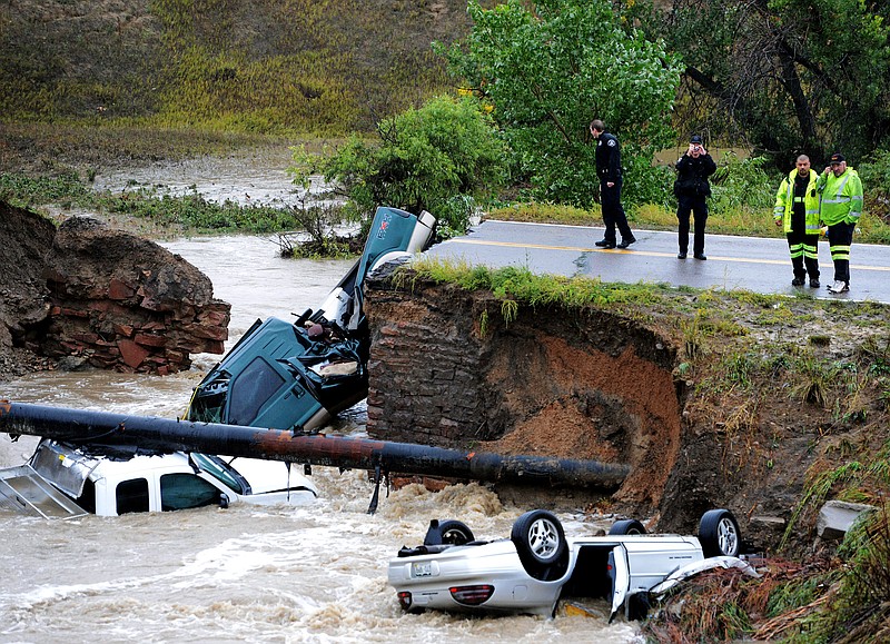 Officials investigate the scene of a road collapse Thursday at Highway 287 and Dillon at the Broomfield/Lafayette border, Colo., that sent three vehicles into the water after flash flooding. The National Weather Service has warned of an "extremely dangerous and life-threatening situation" throughout the region.