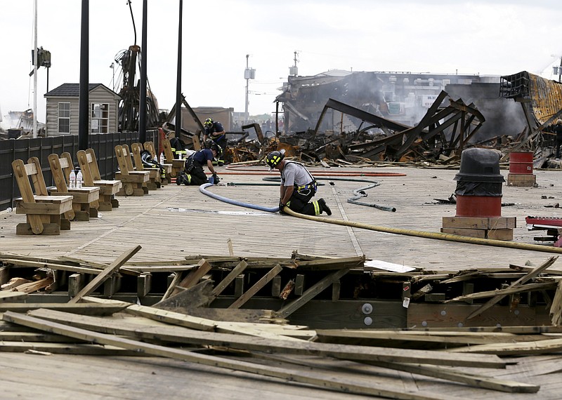 A firefighter unhooks two hoses Friday at the place where emergency workers broke through the recently repaired boardwalk in efforts to stop a fire that broke out a day earlier at the Seaside Park boardwalk in Seaside Park, N.J.