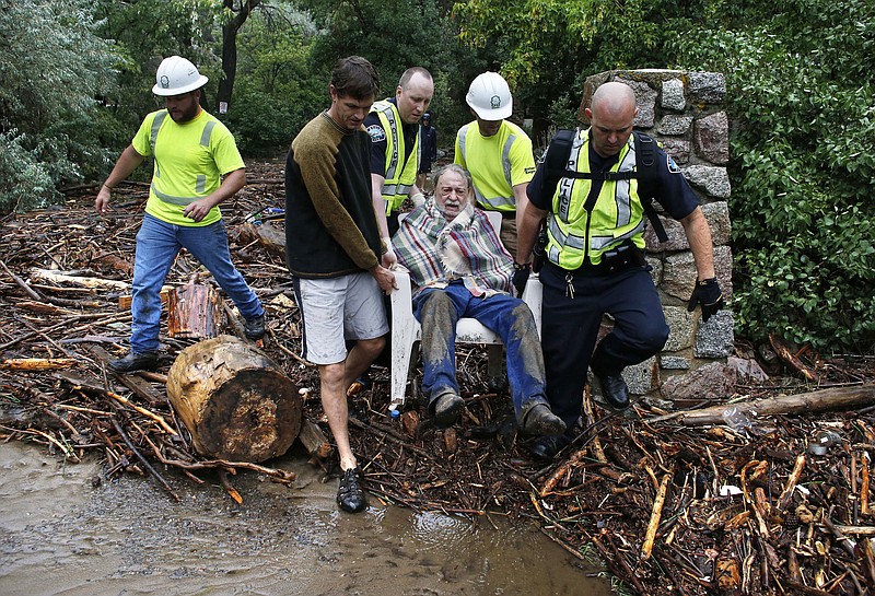 Will Pitner is rescued Friday by emergency workers and neighbor Jeff Writer, left, after a night trapped sheltering outside on high ground above his home as it filled with water from a surge of water, after days of record rain and flooding, at the base of Boulder Canyon, Colo. Flash flooding in Colorado has left at least four people reportedly dead and the widespread high waters have hampered emergency workers' access to affected communities as heavy rains hammered northern Colorado.