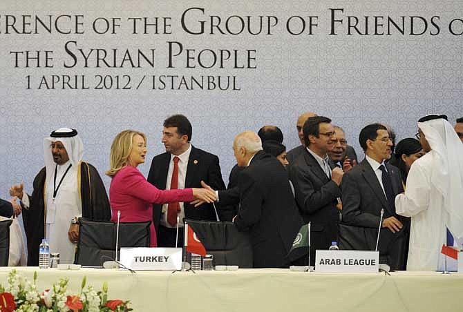 In this April 1, 2012, file photo, then-U.S.Secretary of State Hillary Rodham Clinton speaks with an Arab official as she arrives to join foreign ministers from dozens of countries gathered to set conditions for a new Syria. 