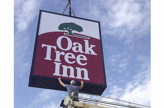 Nathan Libbert with Bee Seen Signs lowers the new Oak Tree Inn sign into place at 1710 Jefferson St. in Jefferson City.
