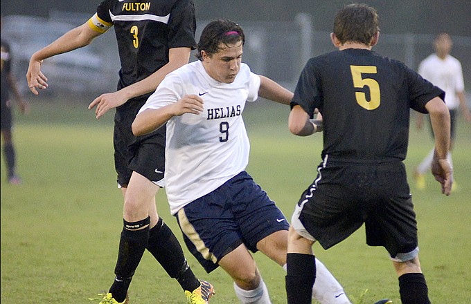 Helias' Nathan Mercurio (left) shoots the ball through the legs of Fulton's Caleb Lee for the only goal in the first half of Tuesday's game at the 179 Soccer Park.