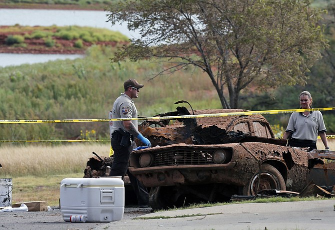 Law enforcement officials from multiple agencies Wednesday examine the two cars pulled from Foss Lake, in Foss, Okla. The Oklahoma State Medical Examiner's Office says authorities have recovered skeletal remains of multiple bodies in the Oklahoma lake where the cars were recovered.