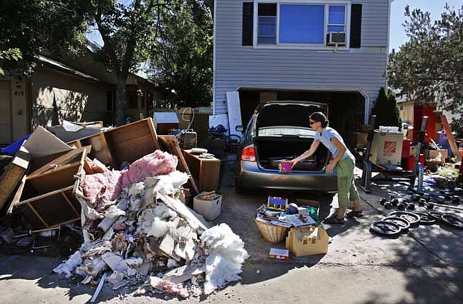 Shanda Roberson disposes of destroyed items from her home, after recent floods swept through Longmont, Colo., Wednesday Sept. 18, 2013. As water recedes and flows east onto the Colorado plains, rescuers are shifting their focus from emergency airlifts to trying to find the hundreds of people still unaccounted for after last week's devastating flooding. 