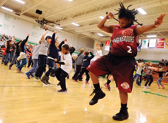 Kiki Smith of the Harlem Ambassadors leads the way as she, her teammates and dozens of children dance to "Gangnam Style" during halftime in an exhibition basketball game to raise funds for Capital City CASA (Court-Appointed Special Advocates). The Ambassadors return next week, playing another game on Monday in support of CASA.