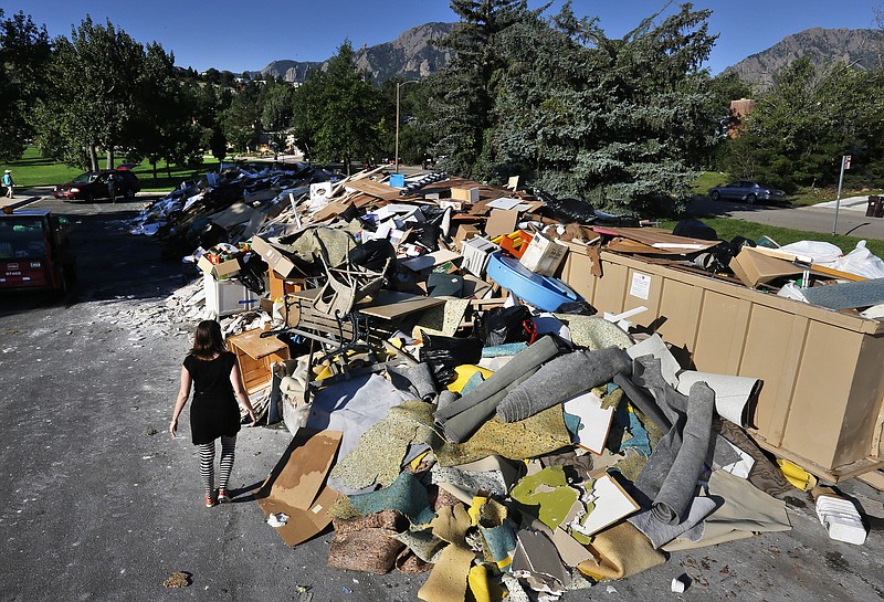 A woman looks Friday for reclaimable wood from a heap of household flooring, furniture and other items destroyed by flooding the previous week, in Boulder, Colo. The flood recovery process is underway along the front range of Colorado as people clean out flooded homes and businesses.