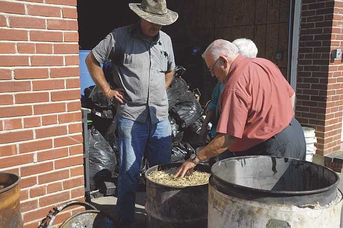 Jack Ryan, organizer of the local Project NEEED (Nutrition, Energy, Environment, and Economic Development), examines the biomass which will be used in the pyrolysis chamber at Lincoln University to become biochar as technician Phil Markway waits.