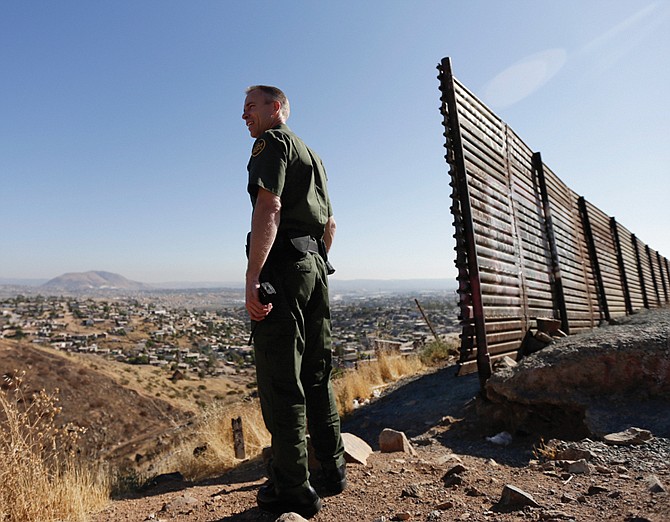 US Border Patrol agent Jerry Conlin looks out over Tijuana, Mexico, behind, along the old border wall along the US - Mexico border, where it ends at the base of a hill in San Diego. 