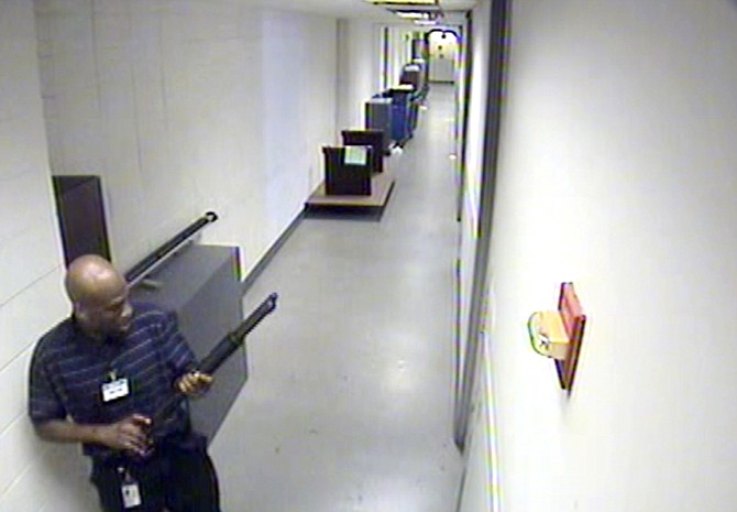 Aaron Alexis moves through the hallways of Building 197 at the Washington Navy Yard on Sept. 16, in Washington, carrying a Remington 870 shotgun. Alexis, a 34-year-old former Navy reservist and IT contractor, shot and killed 12 people inside a Navy Yard building last week before being killed in a shootout with police.