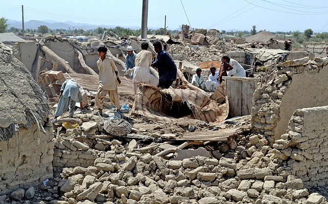 Pakistani villagers look for belongings Wednesday amid the rubble of their destroyed homes following an earthquake in the remote district of Awaran, Baluchistan province, Pakistan. 