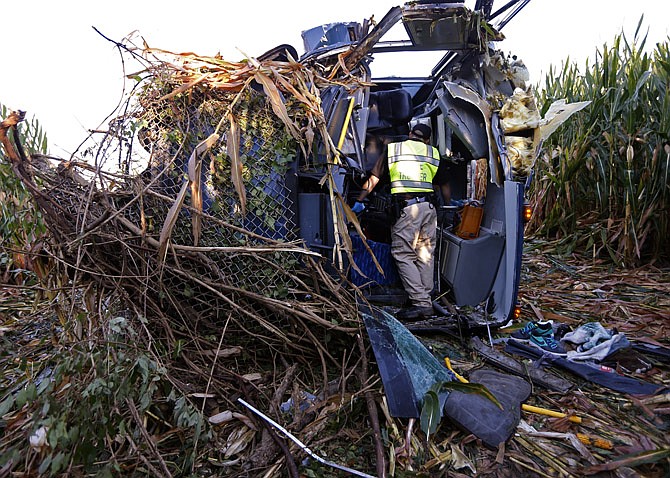 An Ohio Highway State Patrol officer investigates the scene of an overturned Greyhound bus following a crash along interstate 75 in Liberty Township, Ohio. An investigation report released Thursday, shows the driver, Dwayne Garrett, told police at the scene of the Sept. 14 accident that he had been drinking coffee, started coughing, then lost consciousness.