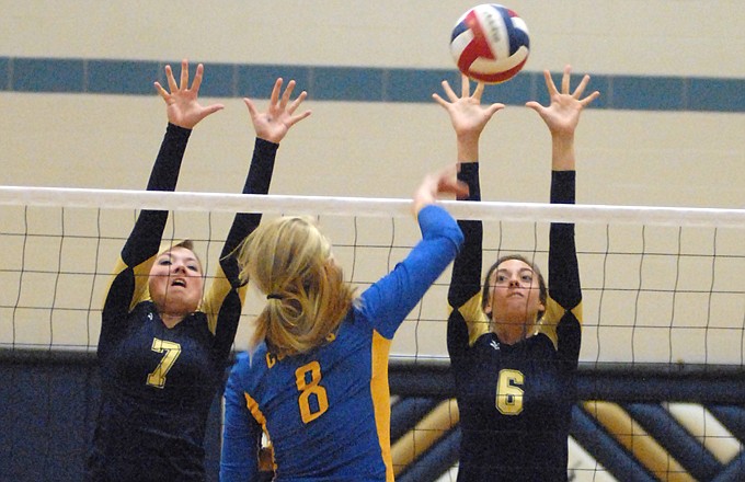 Fatima's Shelby Thoenen (8) hits the ball as Helias' Lindsey Griggs (8) and Molly Sandbothe try for the block Thursday night at Rackers Fieldhouse.