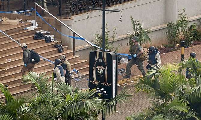 Unidentified armed foreigners, accompanied by Kenyan security forces, enter the main entrance of the Westgate Mall on Thursday in Nairobi, Kenya. Working near bodies crushed by rubble in a bullet-scarred, scorched mall, FBI agents began fingerprint, DNA and ballistic analysis Wednesday to help determine the identities and nationalities of victims and al-Shabab gunmen who attacked the shopping center, killing more than 60 people.