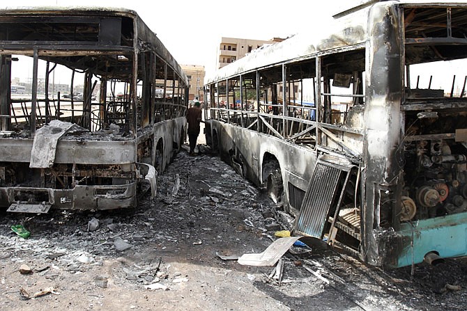 A Sudanese man looks at destroyed buses after rioters torched a fuel station Thursday in Khartoum, Sudan. Sudanese authorities have deployed troops around vital installations and gas stations in Khartoum following days of deadly rioting over gas price hikes.