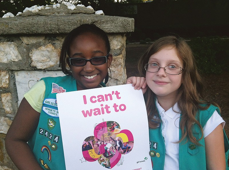 Natalie Harrison, left, and Jasmine Barnett of Troop 2424 hold a promotional poster for their organization outside of Matthews Elementary School in Charlotte, N.C.