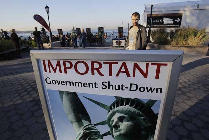 A park ranger, who declined to give his name, reads a sign announcing the closing of the Statue of Liberty, Tuesday, Oct. 1, 2013, in New York. Congress plunged the nation into a partial government shutdown Tuesday as a long-running dispute over President Barack Obama's health care law forced about 800,000 federal workers off the job, suspending all but essential services.