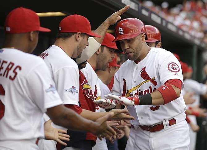 St. Louis Cardinals' Carlos Beltran, right, is congratulated in the dugout by teammates after hitting a three-run home run against the Pittsburgh Pirates in the third inning of Game 1 of baseball's National League division series on Thursday, Oct. 3, 2013, in St. Louis.