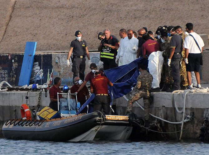 Rescuers lift a body bag Thursday as they reach the port of Lampedusa, southern Italy. At least 114 people died and scores more were missing late Thursday after a crowded fishing boat carrying African migrants from Tripoli caught fire, flipped over and sank, Italian officials said.