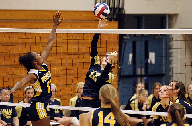 Helias setter Brittney Engelbrecht places her shot just beyond the reach of Battle outside hitter Asia Tiford during the second game of Monday night's match at Rackers Fieldhouse.