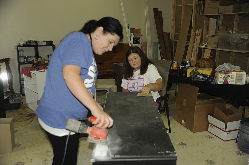 Julie Bolinger and her mother Jo Winkler prepare an old dresser for refinishing in the back room of their new store Winding Road in downtown California. Democrat photo/Michelle Brooks