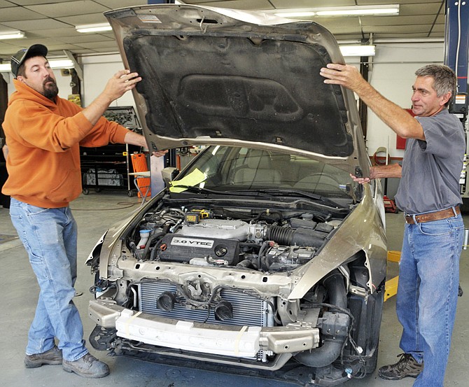 In this October 2013 photo, auto body technicians Lance Wolters, left, and Rich Eichholz remove a damaged hood from a vehicle after it was brought to Kemna Collision Repair. The vehicle suffered damage in a collision with a deer. 