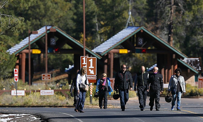 A group of motorcyclists from France walk back out from the main entrance to Grand Canyon National Park Friday after they learned they were not allowed to enter the park on foot as it remains closed to visitors due to the continued federal government shutdown in Grand Canyon, Ariz. 