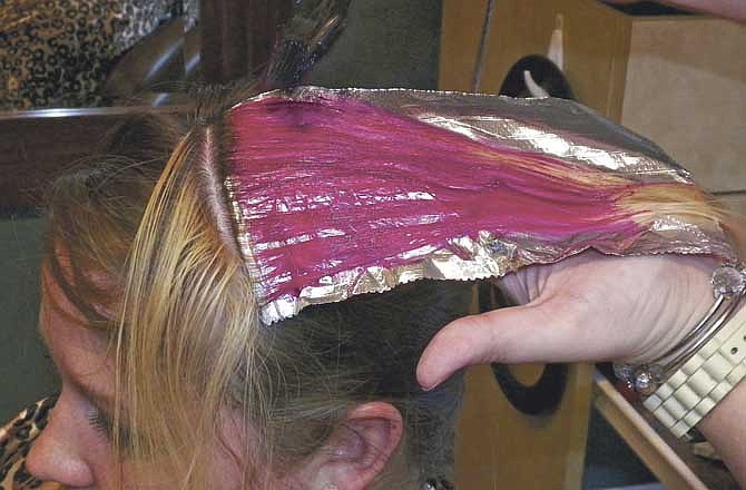 Marshall & Company stylist Alyssa Boss paints the bright pink dye onto News Tribune reporter Jessica Duren's newly bleached hair in support of Breast Cancer research and awareness. Several Jefferson City area salons are offering the pink streaks during the month of October.