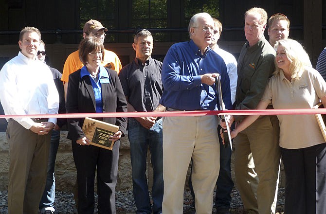 Missouri Gov. Jay Nixon cuts a symbolic ribbon officially signaling the end of a two-year construction project to rebuild the Camp Pin Oak dining lodge in Lake of the Ozarks State Park.
