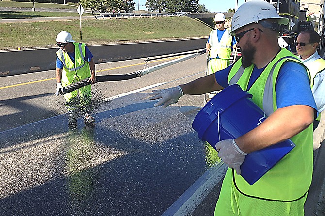 Workers from Truesdell Corporation Midwest of Jefferson City spread a pavement treatment called High Friction Surface Treatment to the eastbound lanes of U.S. 54 near the Madison Street exit on Sunday. The treatment gives drivers a better grip on the road, and is intended to reduce the number of accidents, particularly along curves and in the rain.
