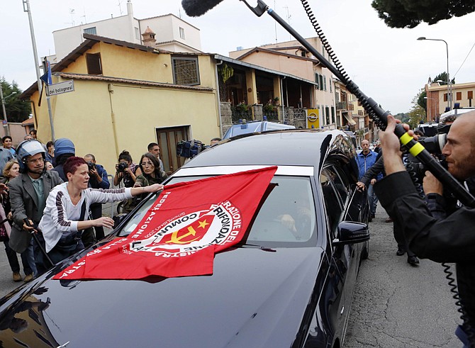 A woman puts a flag of Italian Communist Refoundation Party on the hearse carrying the coffin of Nazi war criminal Erich Priebke as it arrives Tuesday at the Society of St. Pius X. Hundreds of people shouting "murderer" and "executioner" jeered the coffin of Priebke as it arrived.