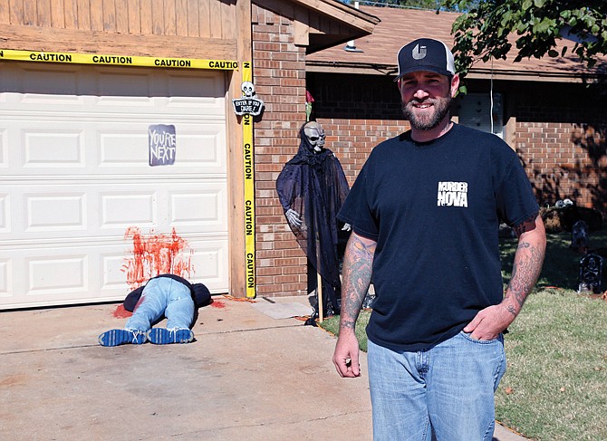 Johnnie Mullins poses with his controversial Halloween display featuring headless dummies dressed in his work clothes at his home in Mustang, Okla. In the display, one dummy lies along a blood-stained garage door with a sign reading "you're next" above it, and another, not shown, lies under a truck with blood splattered on the driveway. Mullins' wife, Jennifer, said she got the idea for the macabre scene from the social media site Pinterest.