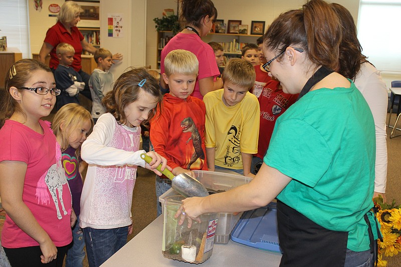 Karly Holland scoops soil into a canister while classmates (From left) Mackenzie Slizewski, Hayzlee Thompson, CJ Mullins and Cameron Ruecker watch during a lesson on how to make healthy soil for growing plants.