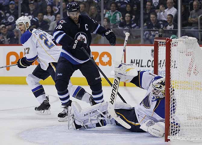 St. Louis Blues goaltender Brian Elliot gets tangled in Winnipeg Jets' Andrew Ladd (16) stick during the second period of an NHL hockey game, Friday, Oct. 18, 2013 in Winnipeg, Manitoba.