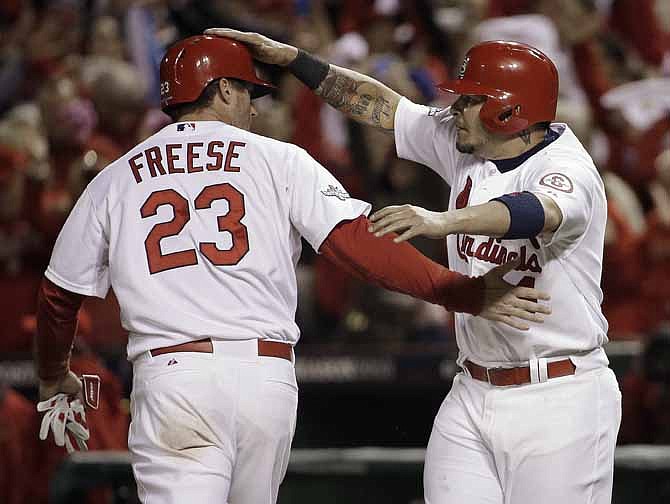 St. Louis Cardinals' David Freese and Yadier Molina celebrate after both scored on a hit by Shane Robinson during the third inning of Game 6 of the National League baseball championship series against the Los Angeles Dodgers, Friday, Oct. 18, 2013, in St. Louis.