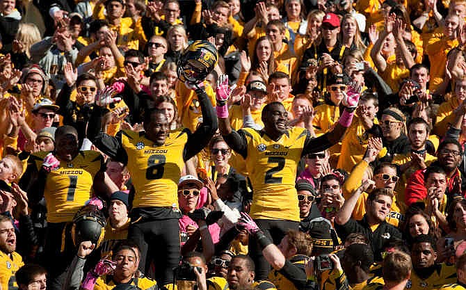 Missouri's L'Damian Washington, right, Darius White, center, and John Gibson, left, celebrate with fans after they defeated Florida 36-17 in an NCAA college football game Saturday, Oct. 19, 2013, in Columbia, Mo.